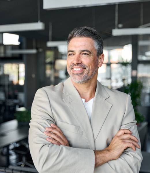 Happy proud mid aged mature professional business man ceo executive wearing suit standing in office arms crossed looking away thinking of success, leadership, corporate growth. Vertical
